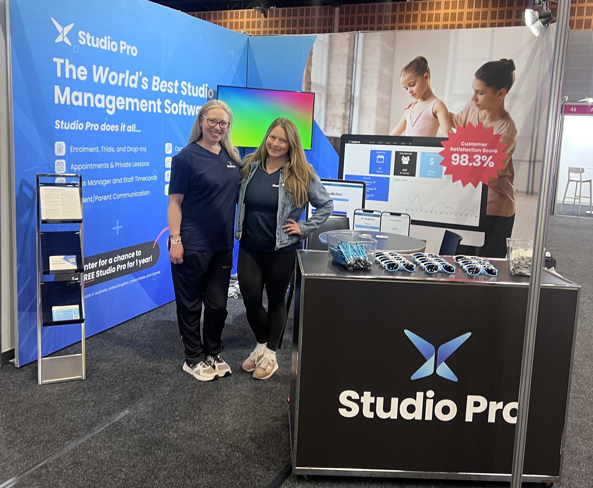 Two Studio Pro staff members at a booth promoting Studio Pro